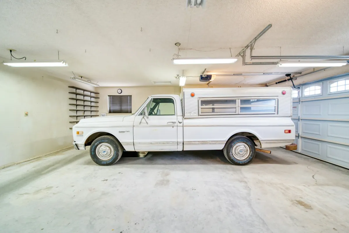 Classic pickup truck parked in a clean, bright garage with a light gray floor